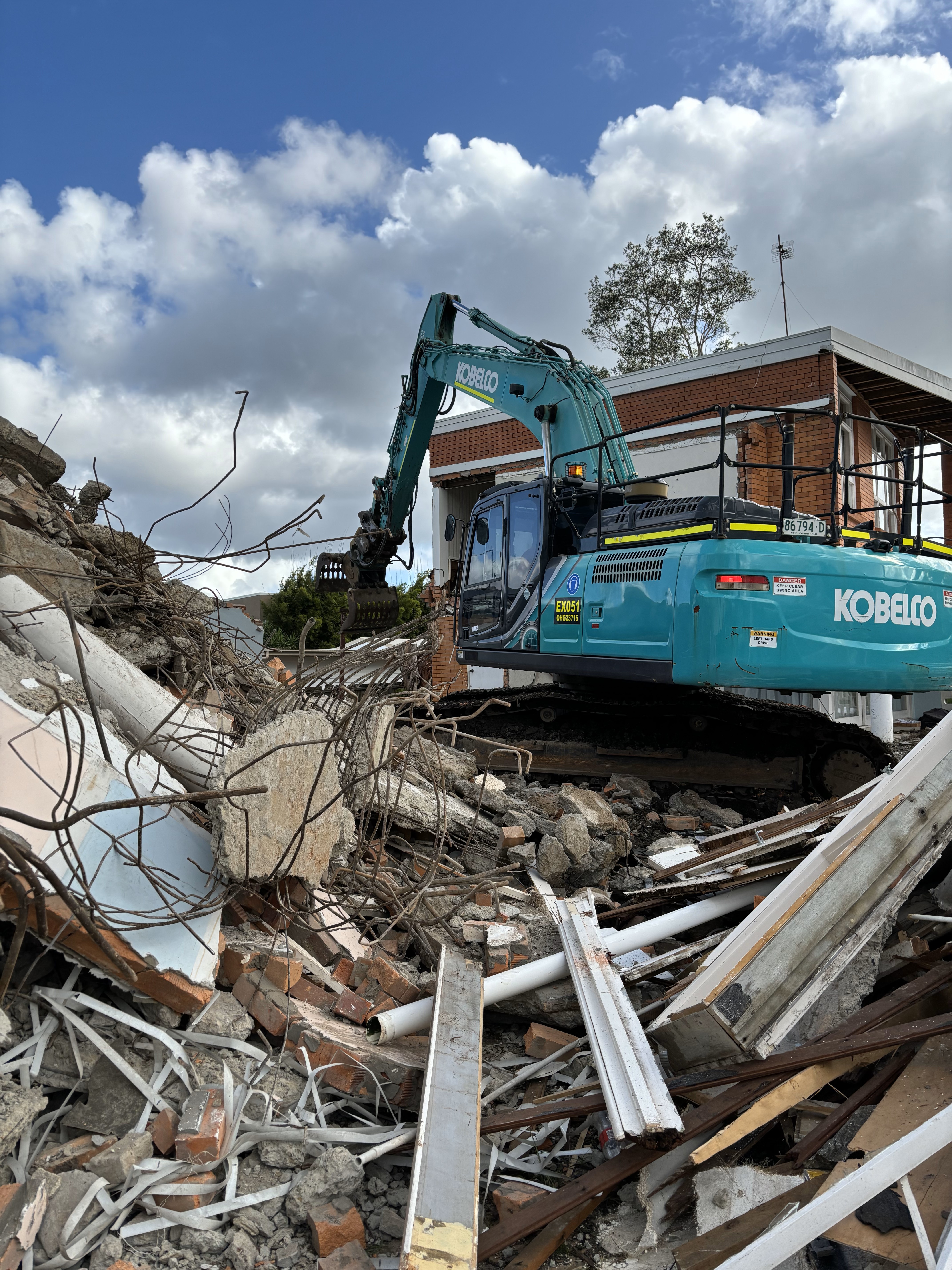 Blue CAT heavy demolition machine demolishing a residential house