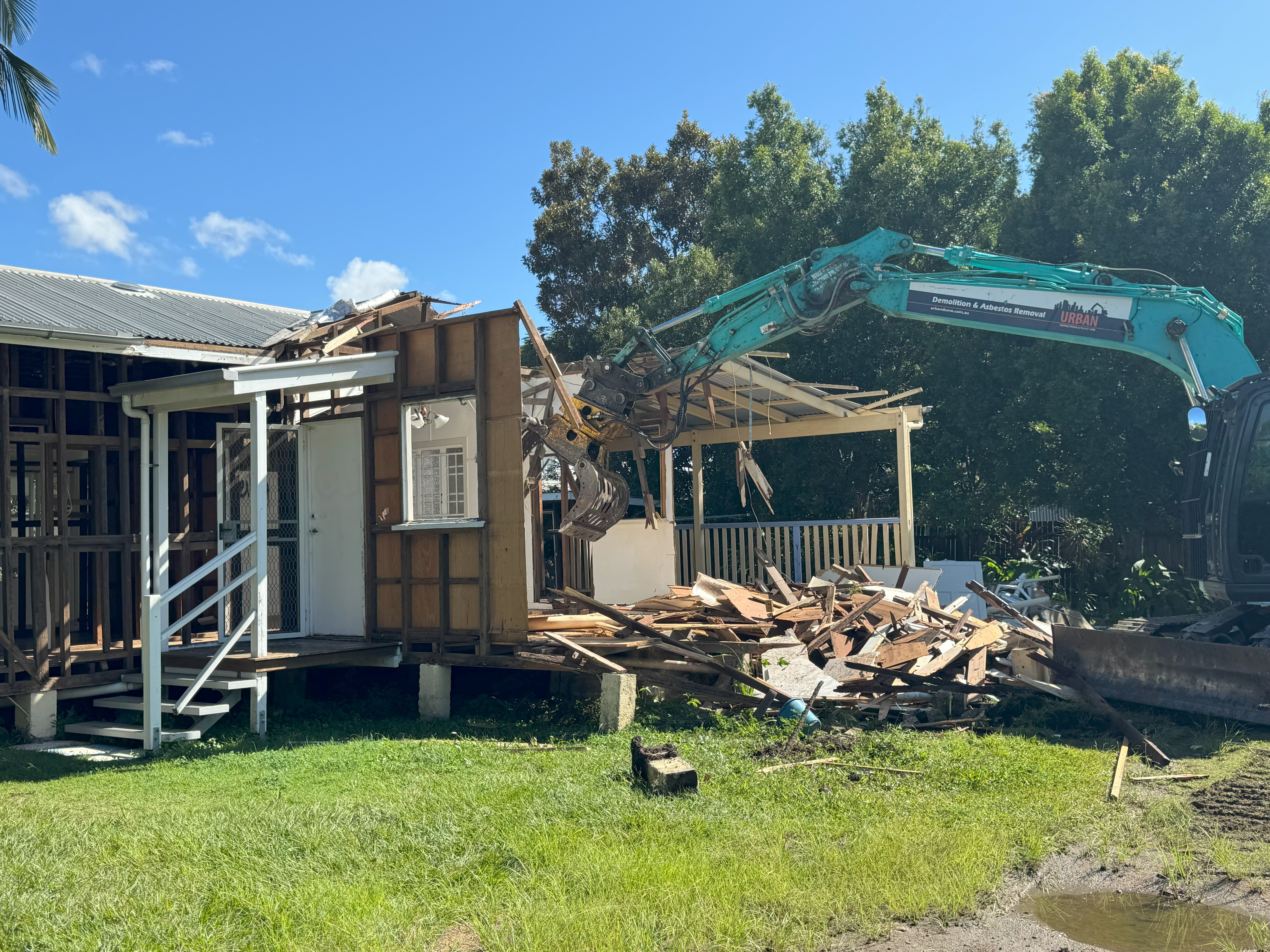 Yellow CAT heavy demolition machine demolishing a commercial brick building by Urban Demolitions services.