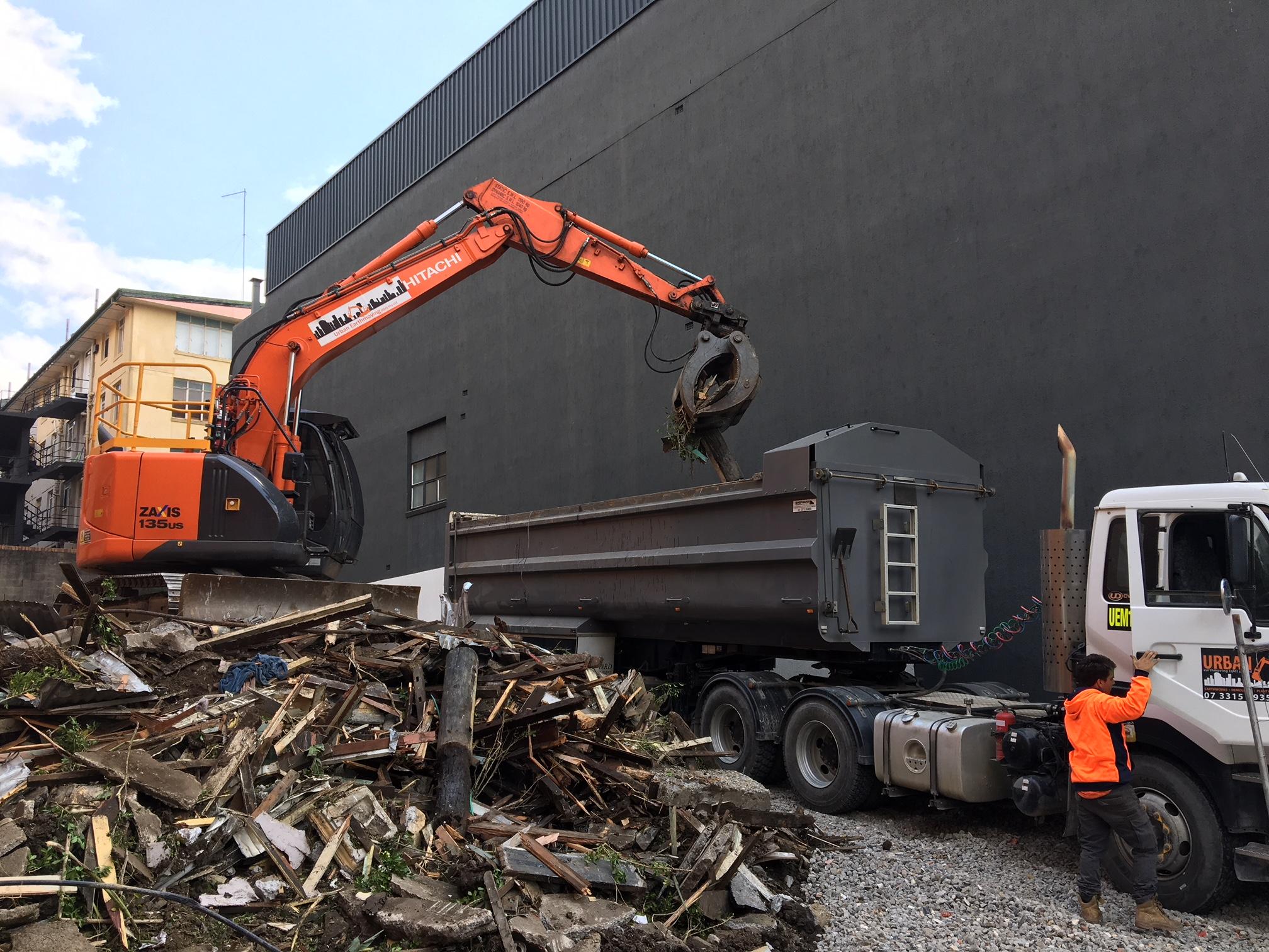 Brisbane CBD Demolition Large orange excavator scooping debris into the back of a truck