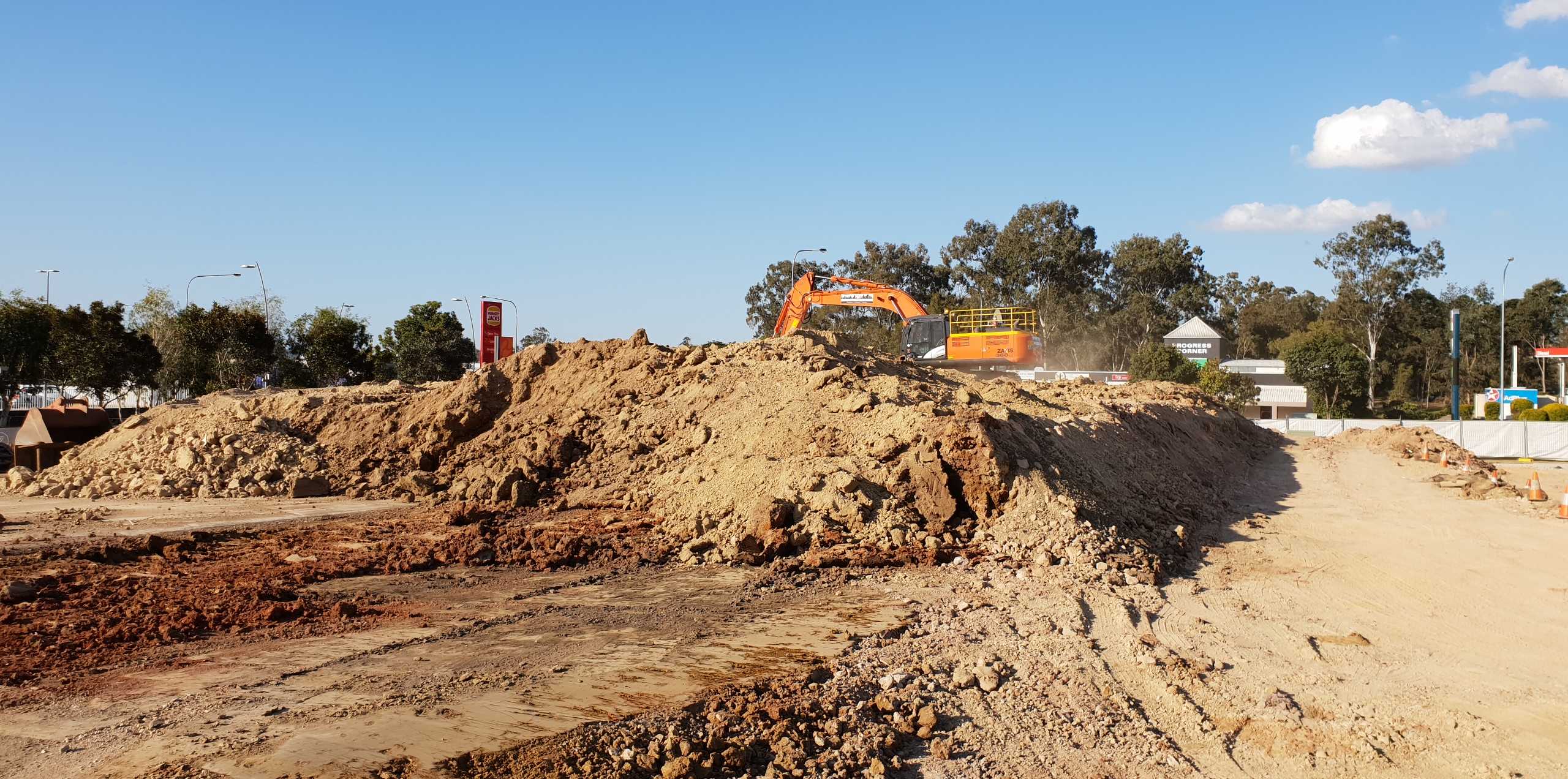 Richlands Bulk Earthworks An orange excavator in a demolition site scooping up dirt