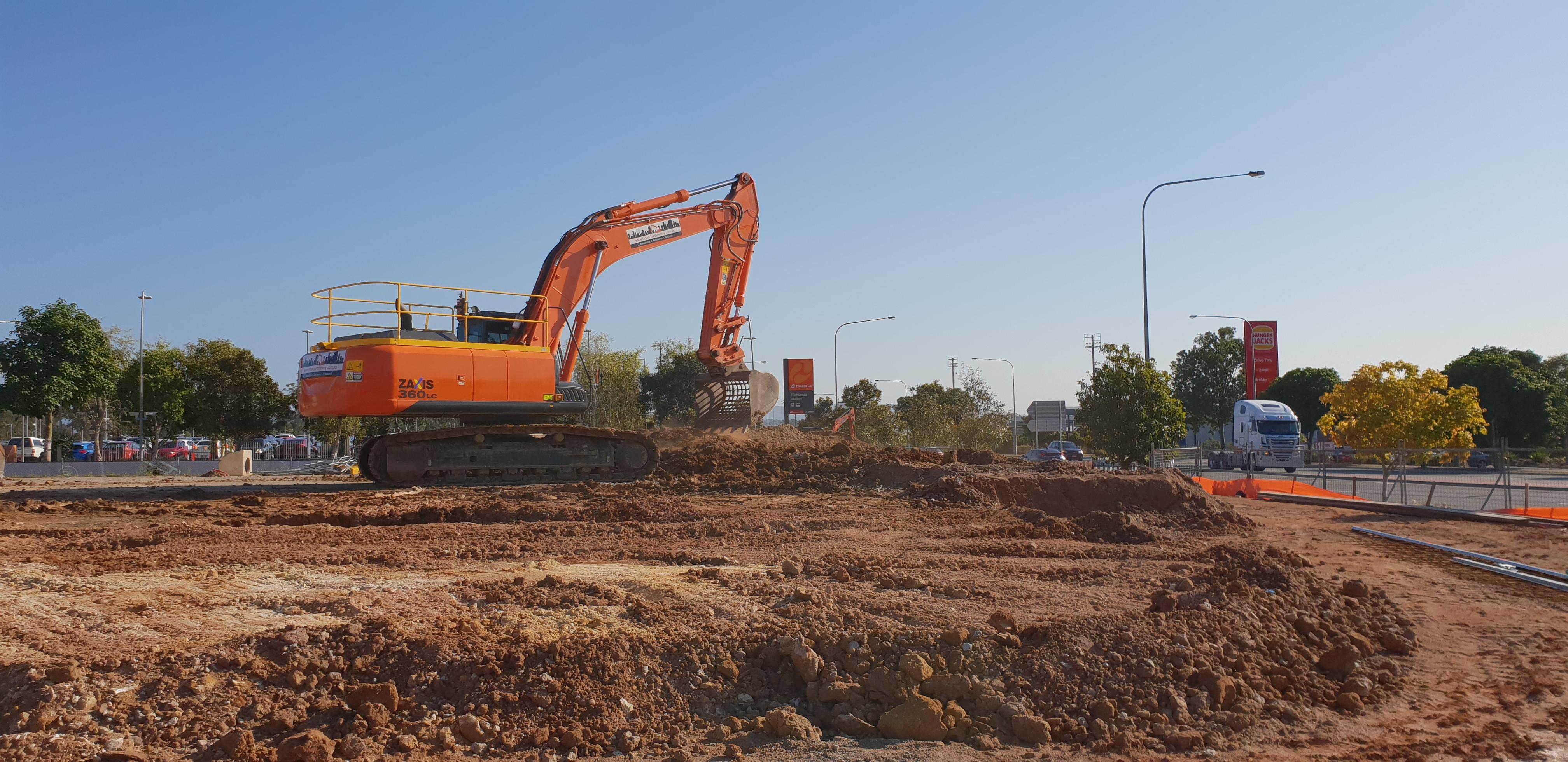 Richlands Bulk Earthworks A large orange excavator scooping up dirt in a demolition site
