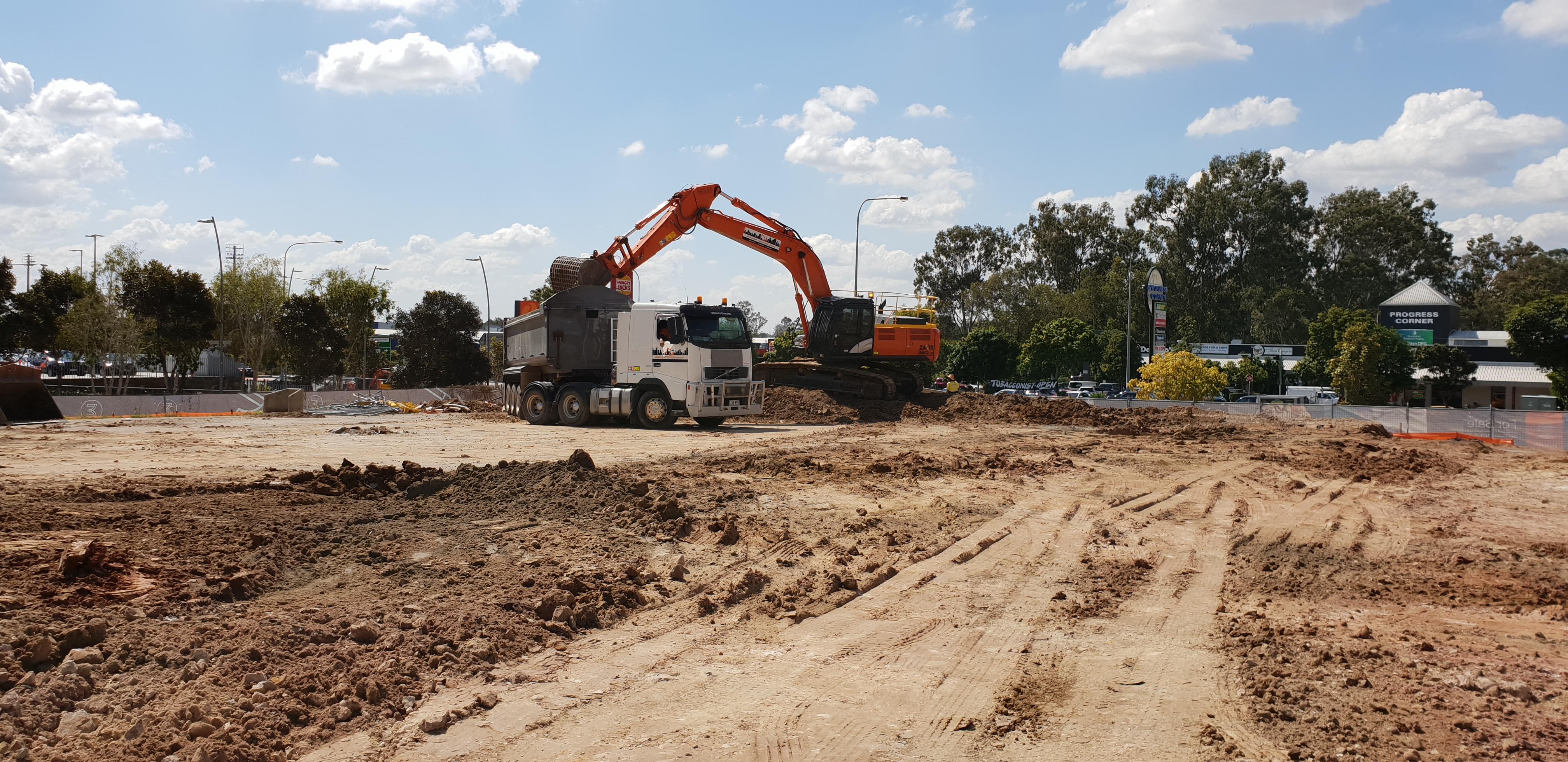 Richlands Bulk Earthworks An excavator in the background unloading dirt in the back of a truck