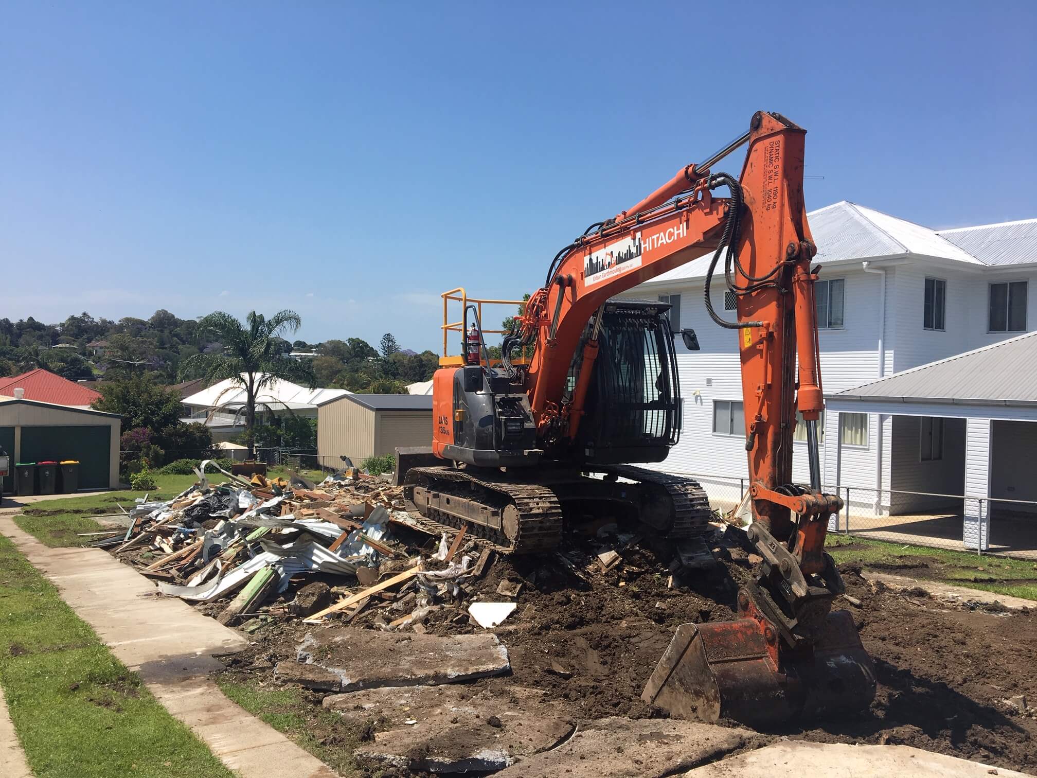 An excavator scooping debris from a demolished house 