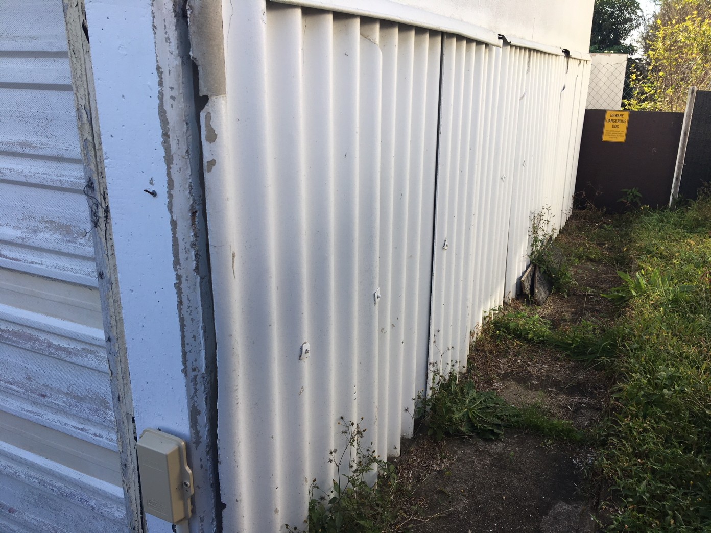Asbestos Removal Services Brisbane White corrugated iron wall on the side of a house