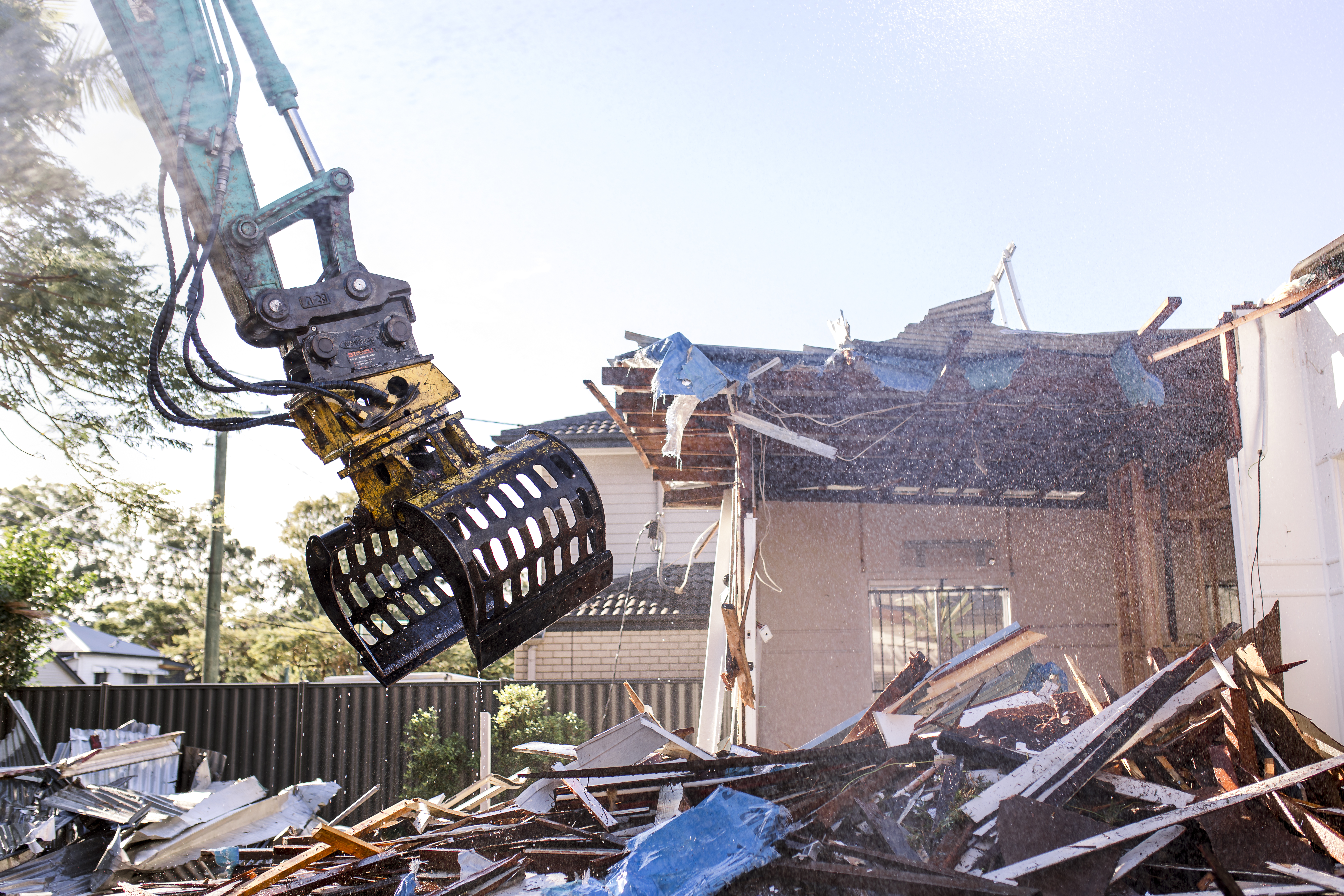 Demolition service in Brisbane Digger demolishing brick dwelling with an excavator.
