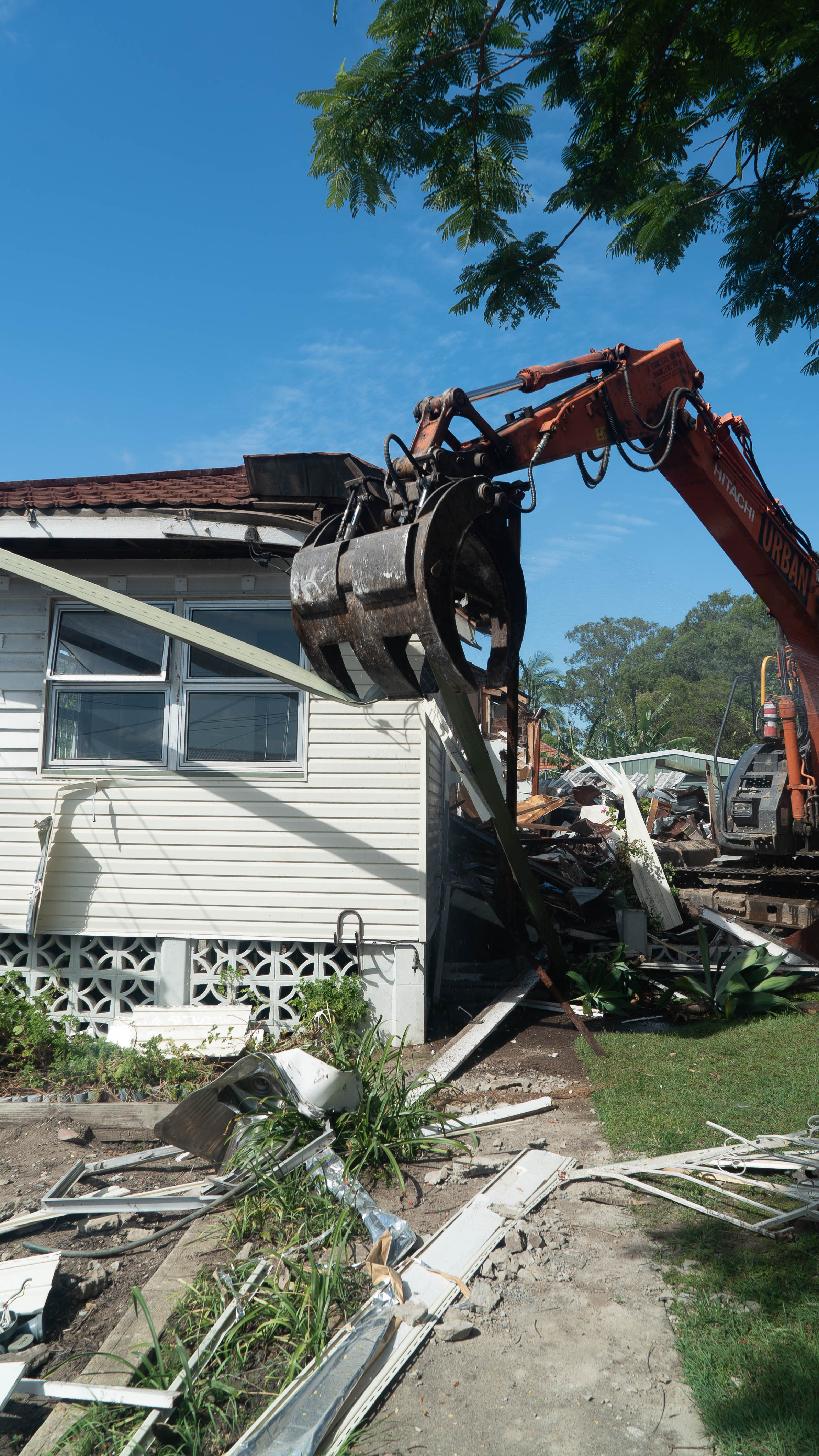 Residential house being demolished by an excavator during a demolition service brisbane.
